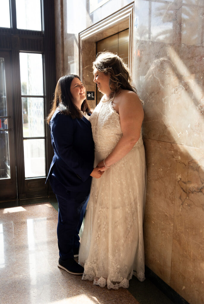 Two women look at each other at San Diego county courthouse wedding by elevator