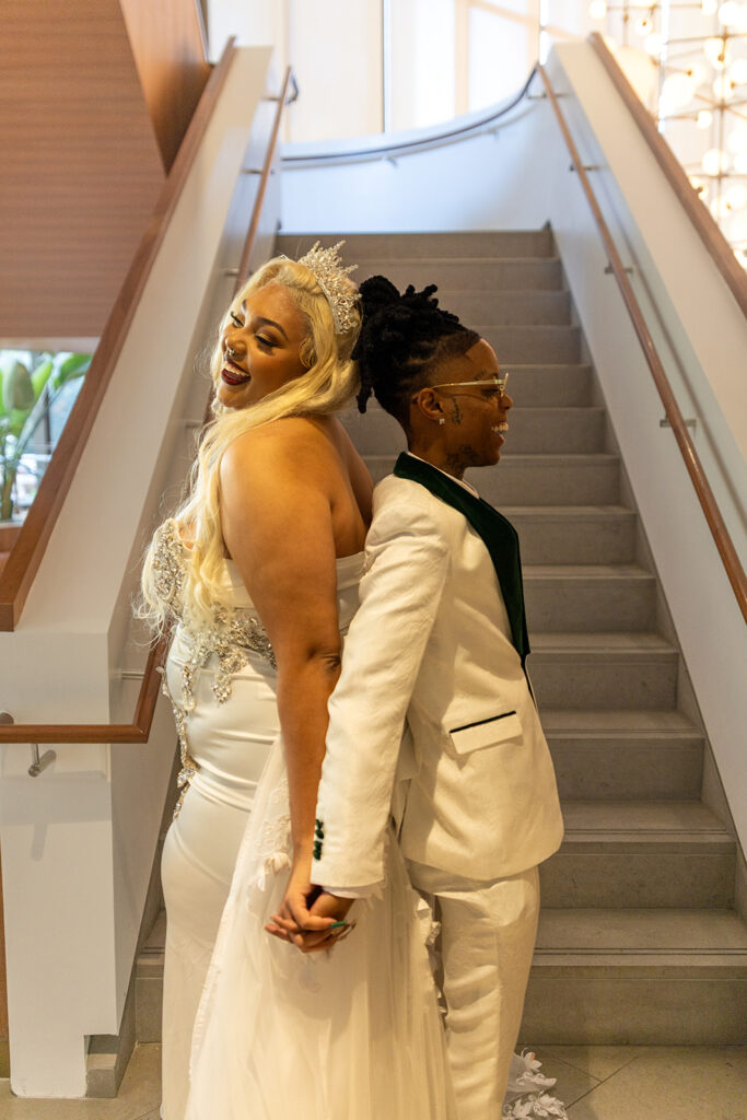 Two brides back to back holding hands for their first touch at intimate elopement