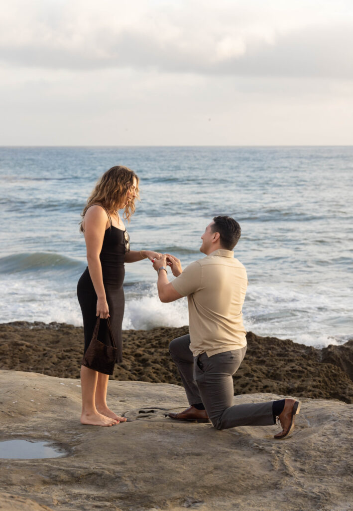 Couple kneeling at Sunset Cliffs to propose to girlfriend