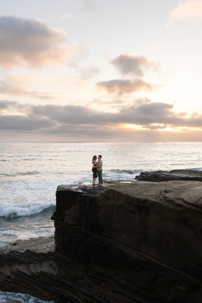 Couple on cliff edge looking at ocean at sunset cliffs