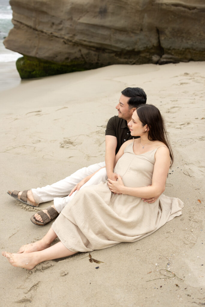 couple looks off at ocean at windansea beach during san diego maternity session