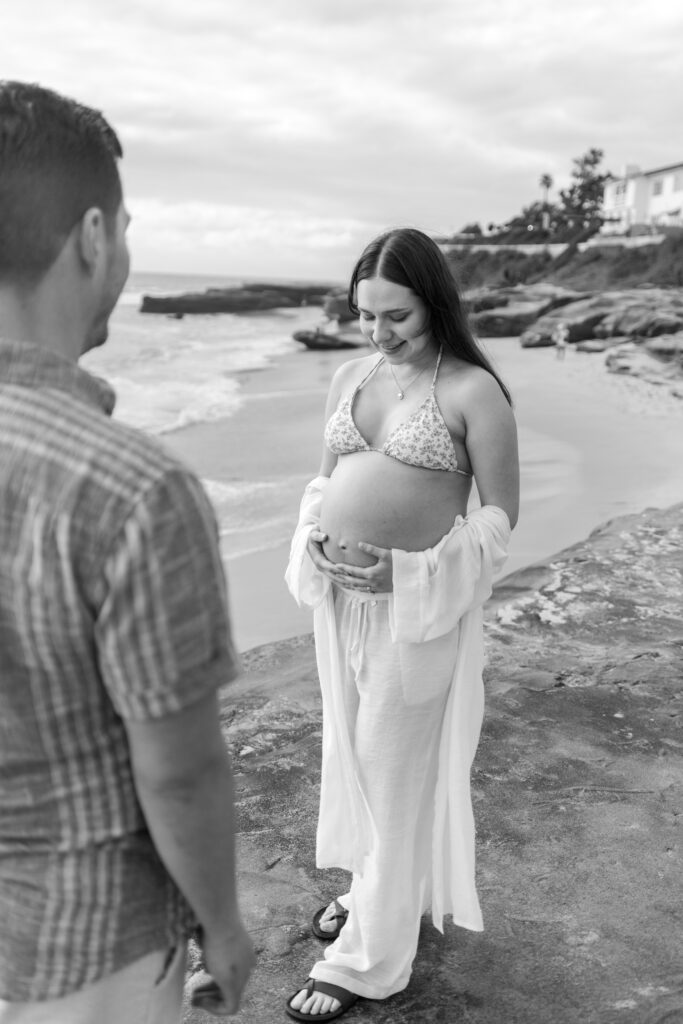 Husband looks at wife for maternity photos windansea beach