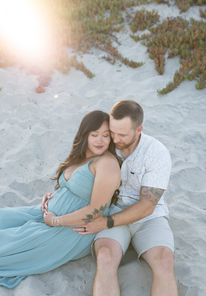 Couple embraces close together for maternity photos at Coronado beach