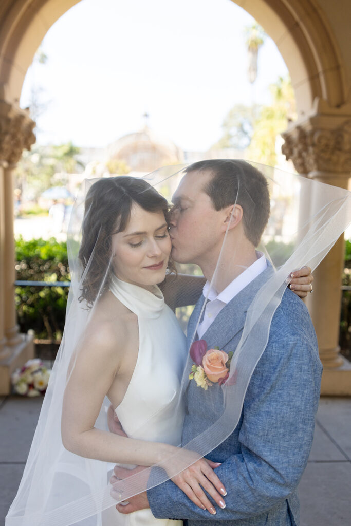 Couple snuggle in under veil at Balboa Park San Diego elopement day